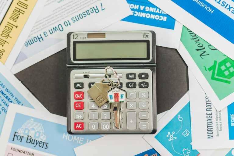 Calculator with keys and real estate documents symbolizes home buying finances.
